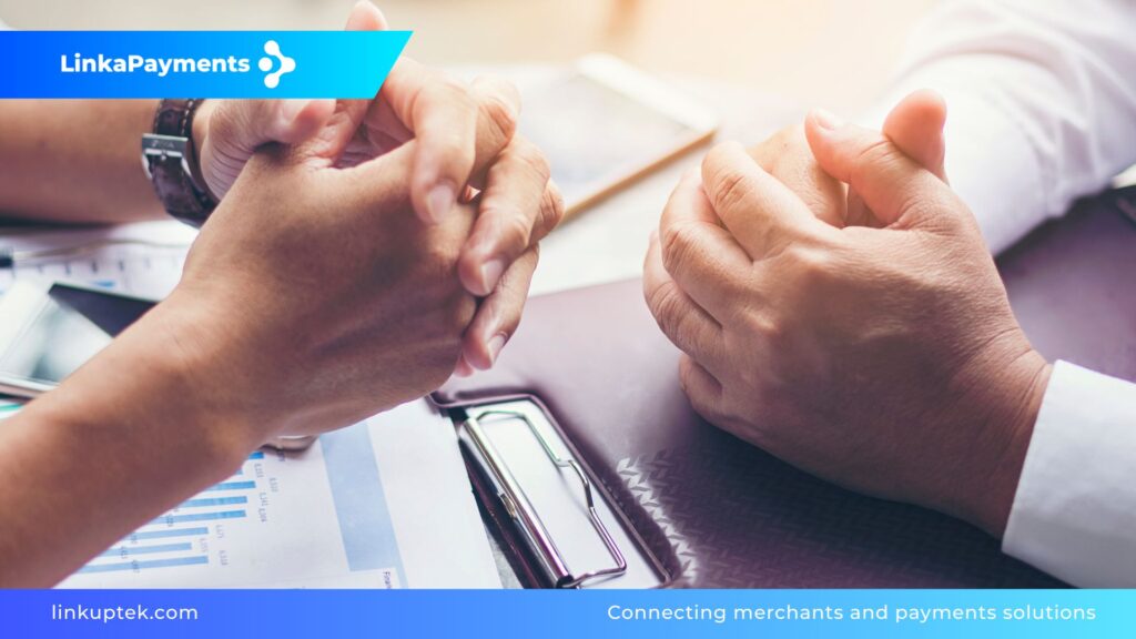 Primer plano de una reunión de negocios con manos sobre una mesa con informes financieros, representando el proceso de due diligence estratégico entre un merchant y su proveedor de pagos.