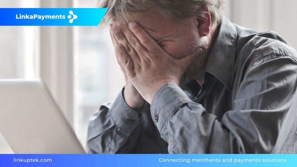 Un hombre con expresión de frustración y estrés se cubre la cara con las manos frente a un ordenador, representando la crisis de un comercio ante el cierre de su pasarela de pagos en 24 horas.